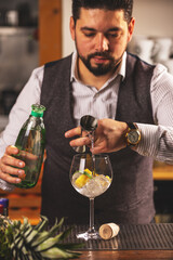 Bartender pouring gin into glass with ice