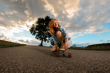Bottom up view. Girl confidently rides longboard in a squat position.