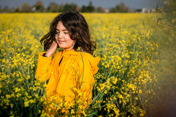 standing in a blooming field happy girl in yellow raincoat