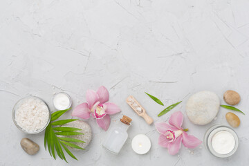 Composition with orchids and massage stones on concrete background, top view