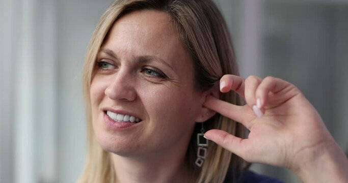 Woman scratches ear with index finger to relieve itch
