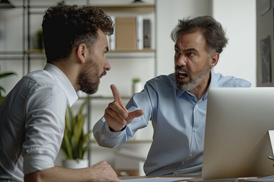 Angry boss criticizing scolding sad male employee for computer mistake incompetence at workplace, mad leader reprimanding rebuking shouting at subordinate lazy worker blaming of bad work in office
