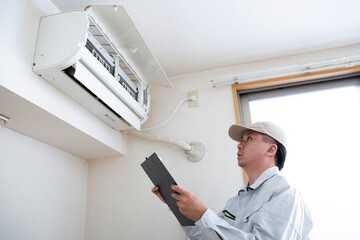 エアコンの修理点検をする業者の若者、日本人