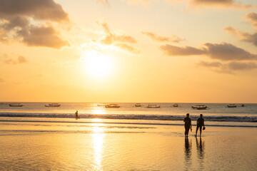 Fantastic sunset on the dream beach of Kuta, small waves setting over the sea and the reflection of...
