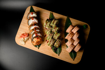 Triple sushi set, top view, presented on banana leaves with seasonings.