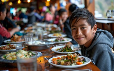 Fototapeta premium A young boy is seated at a table, surrounded by plates of food in front of him