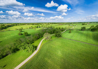 Aerial view of a rural road between green pastures on the grounds of horse farms in central Kentucky