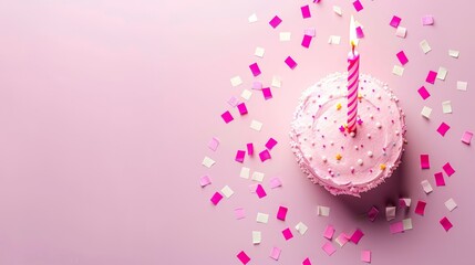   A cupcake with pink frosting, topped with a single candle, surrounded by confetti and sprinkles