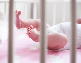 Newborn's delicate feet with visible dry skin. Baby girl in a crib