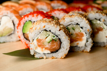 Close up of rolls adorned with tobiko caviar, sesame, and sauce.