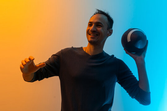 Handsome young man with rugby ball on color background.
