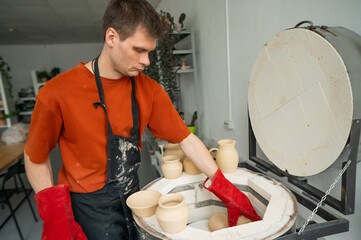 Caucasian man loading ceramic products into a special kiln. 