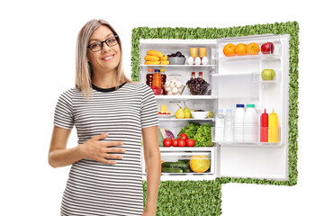 Hungry young woman standing in front of a sustainable fridge