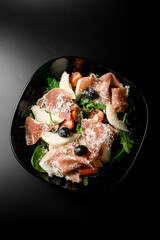 Top view of green salad with olives, tuna, and Parmesan.