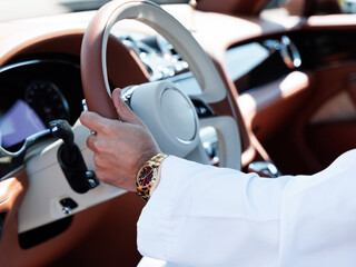 a wealthy sheikh prince driving a luxury car in a white Arabian outfit