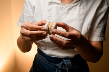 Makes macarons with skilled hands specialist in blue jeans and a white T-shirt