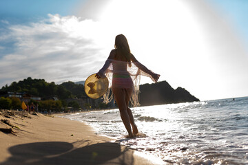 Happy woman walking on beach at sunset.Beautiful female happy relax walking on beach near sea when...