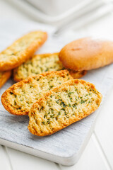 Garlic crisp bread Slices Topped With Herbs on cutting board.