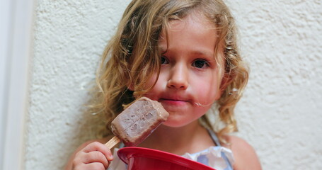 Cute adorable little girl eating chocolate ice-cream snack