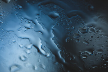 visuale macro di gocce d'acqua di pioggia che cadono e scorrono lungo un vetro in trasparenza in...