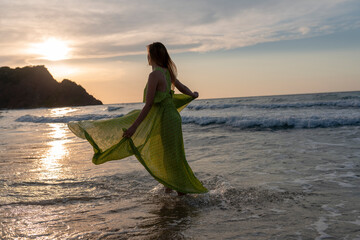 Happy woman walking on beach at sunset.Beautiful female happy relax walking on beach near sea when...