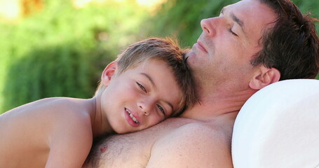 Father and son together small boy laid on dad chest outside