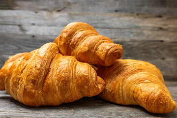 Delicious, fresh croissants isolated on wooden board. French breakfast concept.