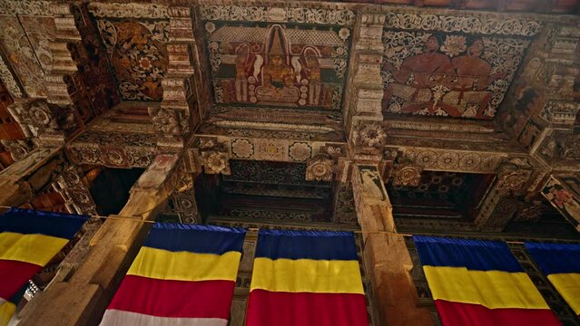Sri Dalada Maligawa, Kandy shows ornate wooden carvings, colorful frescoes, vibrant temple flags. Sacred Buddhist site with historical art in Sri Lanka. Cultural, religious tourism attraction.