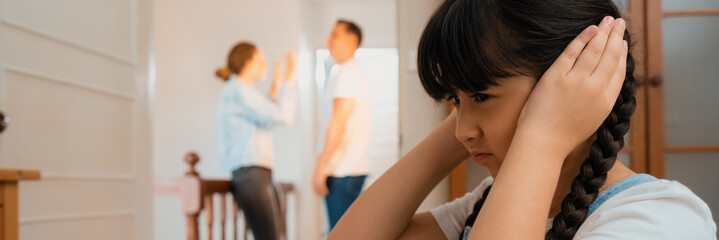 Stressed and unhappy young girl huddle in corner, cover her ears blocking sound of her parent...