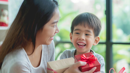 A woman and child are joyfully holding a gift box together, celebrating a special occasion.