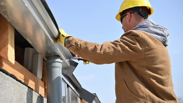Man in Hard Hat Working on Roof Gutters