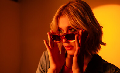 A woman wearing sunglasses is talking on a cell phone in a dark room