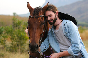Young handsome man hugs a horse.
