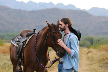 Young handsome man hugs a horse.
