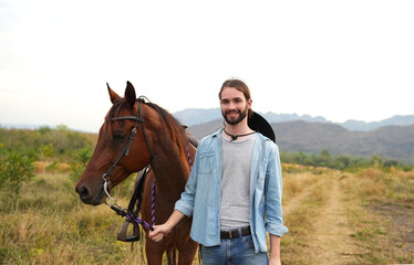 Young handsome man walking with  a horse.
