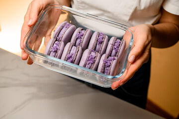 Lilac macarons in a glass container in hands of the girl a white T-shirt top