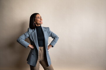 a woman in a blue jacket and brown pants is standing with her hands on her hips