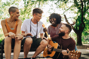 Group of interracial hippie artist having jam session in a park.