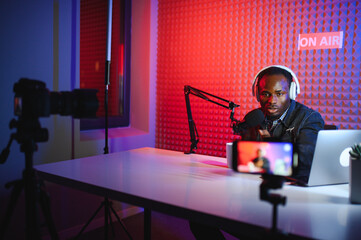 african american vlogger using smartphone to film podcast in studio. blogger with mobile phone,...