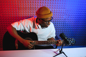 african american man with guitar in recording studio
