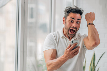 man with mobile phone reacting excited with joy and excitement