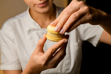 Young girl in a white top makes delicate macaron with her hands