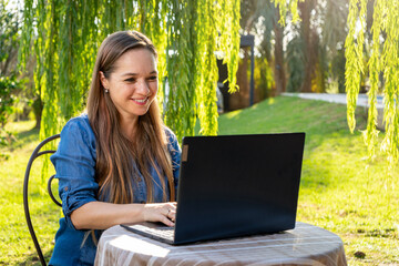 Mujer feliz trabajando con su laptop en exteriores