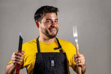 Hombre cocinero contento y entusiasmado sosteniendo sus utensillos de cocina