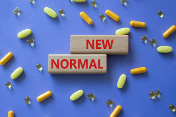 New normal symbol. Wooden blocks with words New normal. Beautiful purple background with pills....
