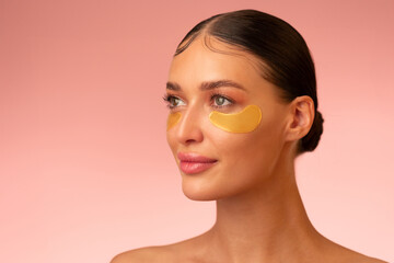 Beautiful young European woman with under eye patches with nourished, glowing skin posing over...