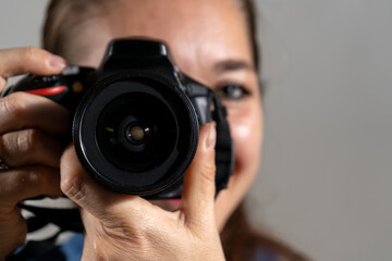 Mujer fotógrafa tomando una fotografía apuntando su cámara al espectador y sonriendo