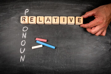 Relative pronoun. Wooden block crossword puzzle and pieces of chalk on a chalkboard background
