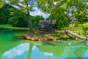 Wooden hut with tree reflections on shore of peaceful lake in Tennessee.