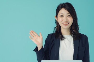 Professional young woman in business attire gesturing a friendly wave against a blue background